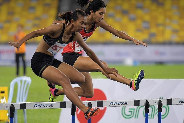 Dipna Lim-Prasad straddling the hurdles alongside Thailand's Jutamas Khonkham. The 26-year-old retained her silver in the 400m Games hurdles at the Bukit Jalil Stadium in Kuala Lumpur despite not being in the best physical and mental shape.
