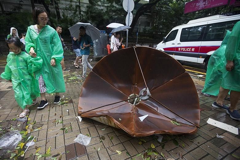 A satellite dish was blown off a rooftop onto the sidewalk in Tsim Sha Tsui, Hong Kong, yesterday. Residents cleaning up the debris at a public housing estate in the district of Heng Fa Chuen, in Hong Kong, after Typhoon Hato swept across the city ye
