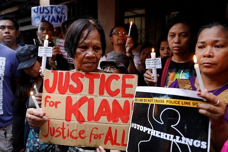 Protesters holding placards and lit candles at the wake of Kian Loyd delos Santos, a 17-year-old high school student, who was among the people shot dead last week in an escalation of President Rodrigo Duterte's war on drugs, in Caloocan city, Metro M