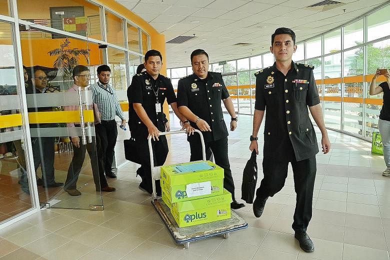 Officers seizing documents during the raid at Universiti Selangor. The probe centres on payments made by Menteri Besar Selangor Incorporated to a private contractor for maintenance work on the campus.