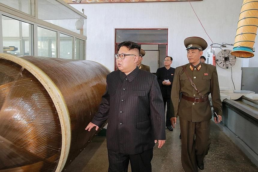 Mr Kim Jong Un being briefed on intercontinental ballistic missile warhead tips and solid-fuel rocket engines during a tour of the Chemical Material Institute of the Academy of Defence Science in North Korea.