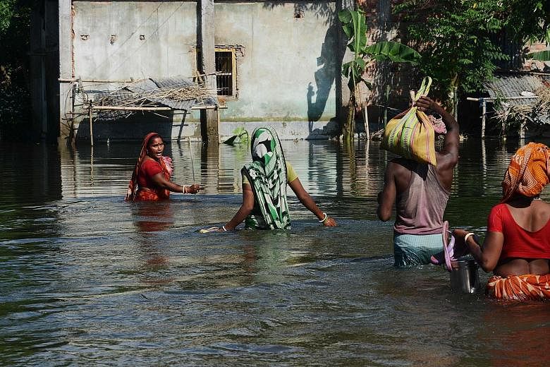 Villagers making their way through floodwaters at Alal village in Malda district, in the Indian state of West Bengal on Wednesday. So far, 152 people have died in the low-lying state.