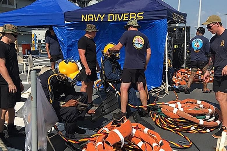 US Navy and Marine Corps divers providing support to USS John S. McCain at Changi Naval Base on Wednesday. Search efforts will now be mostly focused on the damaged destroyer.