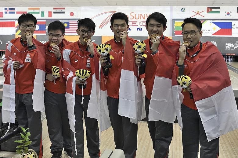 The victorious Singapore men's bowling team celebrate with their gold medals, after recording 6,399 pinfalls to defeat Indonesia (6,280) and Thailand (6,278) at Sunway Pyramid's bowling alley yesterday.