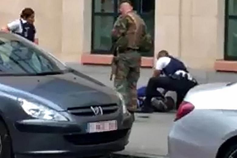 The man who allegedly wounded a soldier with a knife on Friday night in central Brussels lying on the ground after being shot. Police also found a replica gun and two copies of the Quran on him.
