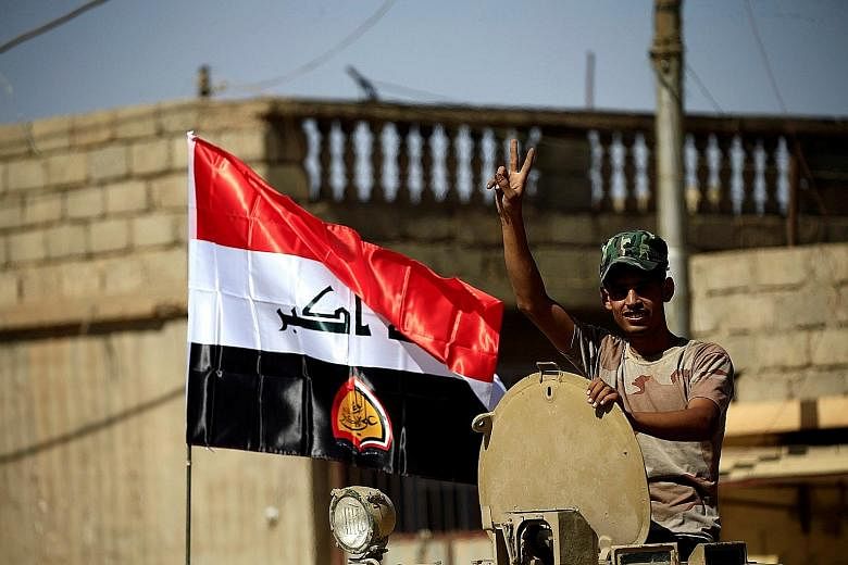 A member of Shi'ite Popular Mobilisation Forces flashing the victory sign in Tal Afar yesterday. The Counter- terrorism Service "liberated the citadel neighbourhood", the Iraqi joint operations command said. A clash between joint troops of Iraqi army