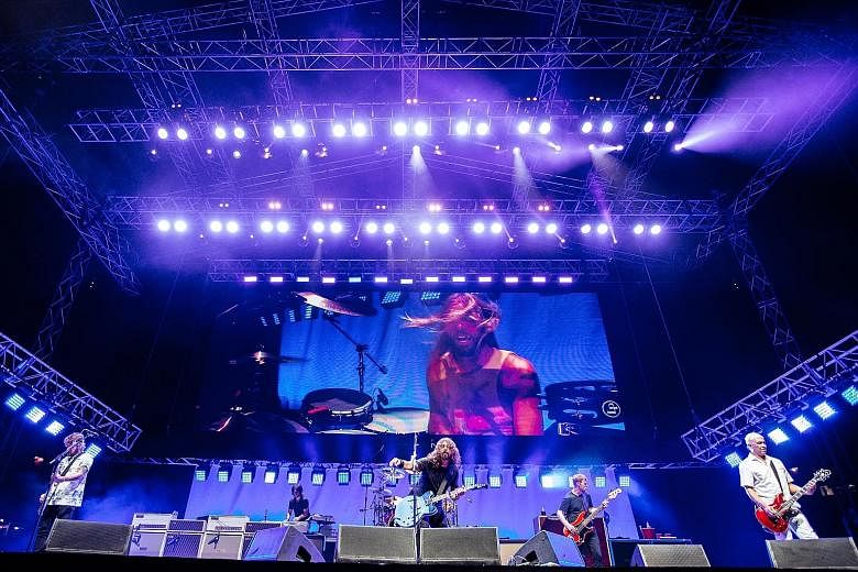 Foo Fighters, comprising (from left) Chris Shiflett, Rami Jaffee, Dave Grohl, Nate Mendel and Pat Smear, with Taylor Hawkins on the screen, rocking it at the National Stadium.