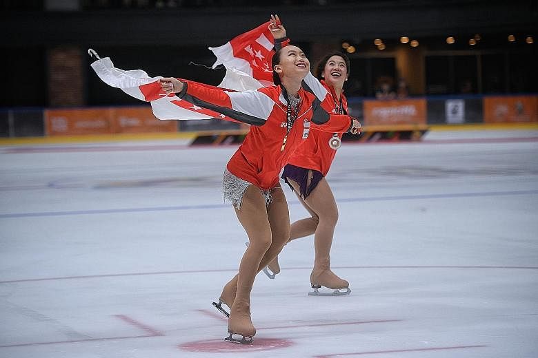 Gold medallist Yu Shuran (left) celebrates with compatriot Chloe Ing as they skate around the ice rink at the Empire City Mall after the women's figure skating competition yesterday.