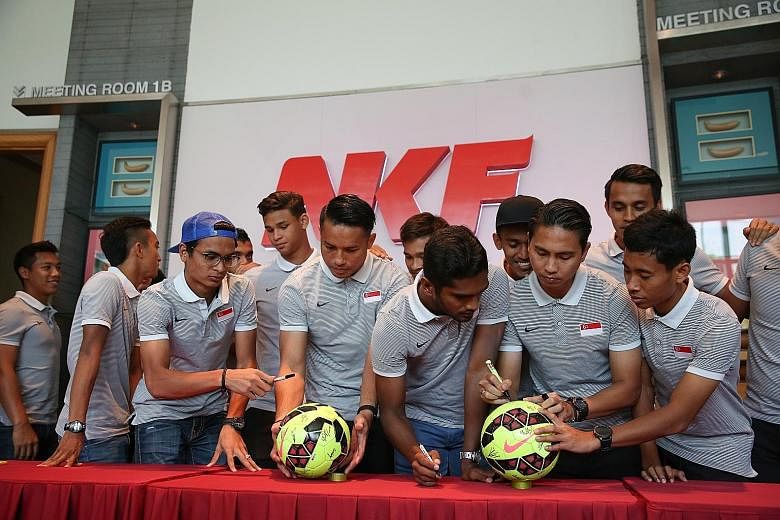 National football captain Shahril Ishak (second from right), vice-captain Hariss Harun (third from right) and the rest of the team signing two footballs, which will be auctioned off later to raise funds for the National Kidney Foundation (NKF). The L