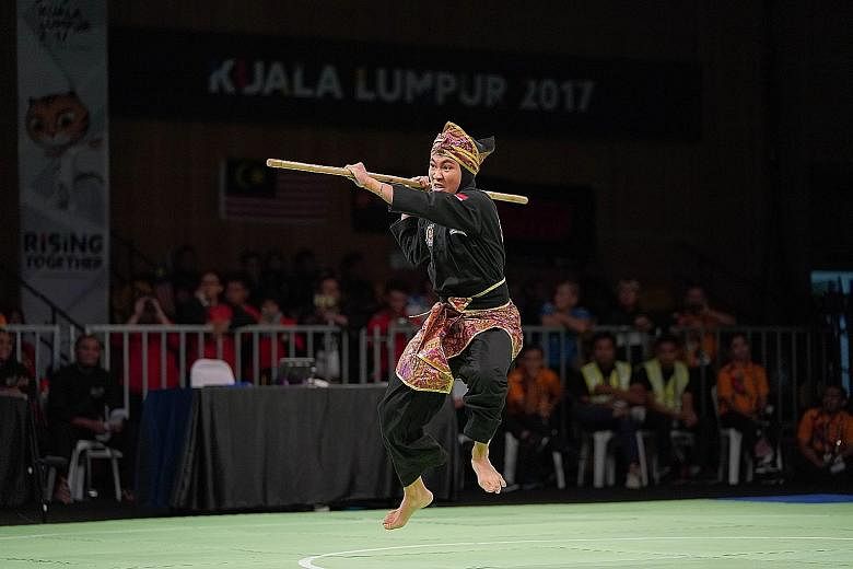 Sheik Farhan in action against Khairul Yaacob of Malaysia in yesterday's Tanding Class J silat final. He beat his opponent 5-0 to win his first Games gold. Nurzuhairah Yazid (below) dazzling in the women's artistic singles with a gold-winning display