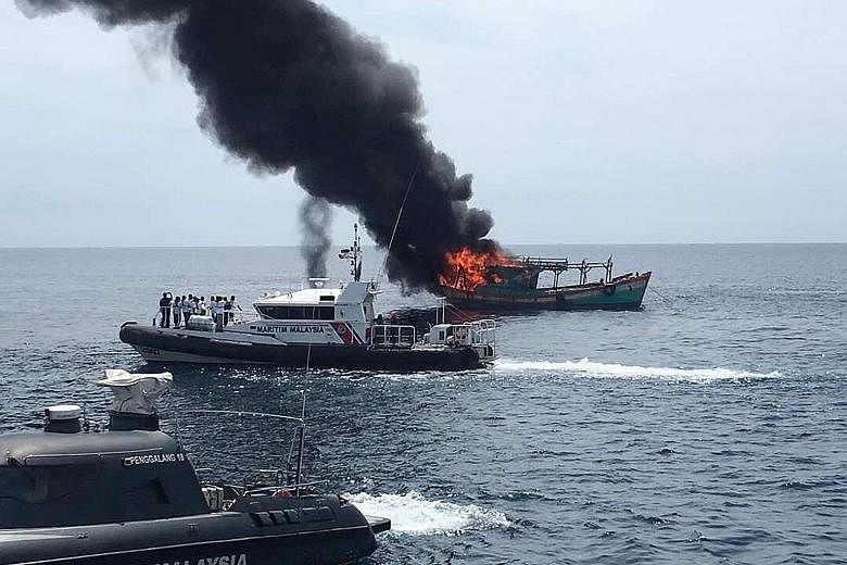 Malaysia's coast guard burning a fishing boat caught in its waters yesterday.