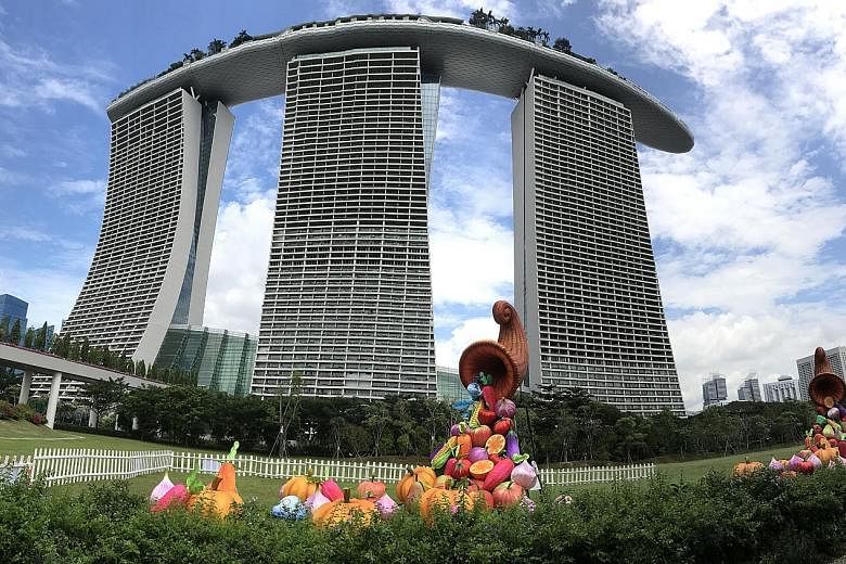 Above: Workers putting up dragonfly-shaped lanterns for the Flight of the Dragonflies installation on the facade of a Supertree at Gardens by the Bay yesterday. Below: The Trail of Abundance installation at the Gardens with its cornucopias of fruit a
