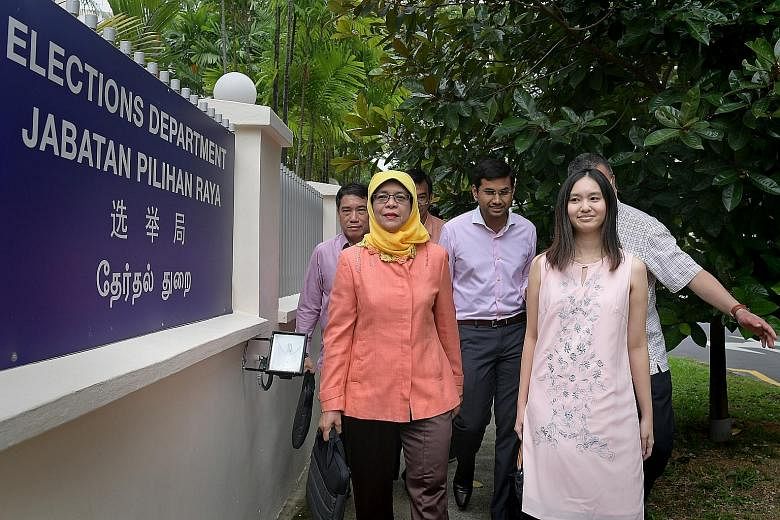 Madam Halimah Yacob arriving at the Elections Department yesterday with election agents Florina Oo and Mohamed Irshad (centre), as well as principal election agent Lawrence Leow (far left).