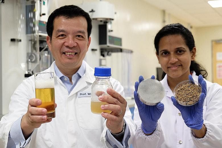 Prof William Chen and PhD student Sachindra Cooray holding (from right) the brewer's spent beer grains, the fermented spent beer grains, the liquid nutrient used to grow yeast, and beer.