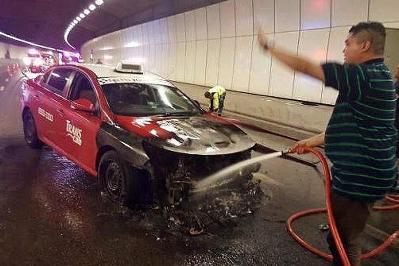 Mr Mohamad Fuad Abdul Aziz (foreground) and Mr Syed Abdillah Alhabshee putting out the taxi fire in the KPE tunnel on Tuesday night.