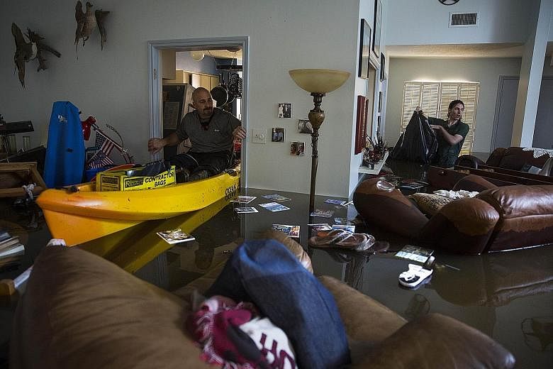 Mr Larry Koser Jr and his son Matthew searching for important papers and heirlooms in their home in the Bear Creek neighbourhood of west Houston, Texas, on Tuesday. The neighbourhood was flooded after water was released from a nearby reservoir.