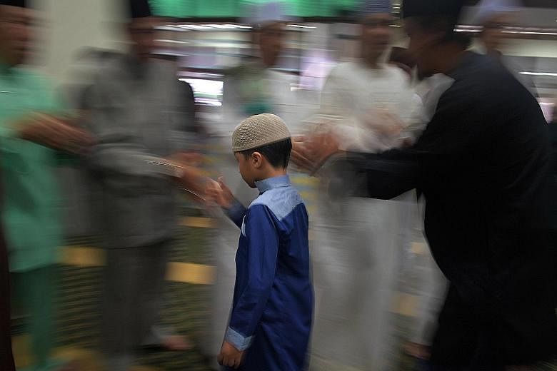 A boy paying his respects to his elders after prayers at the mosque yesterday. Some 850 congregants gathered there to mark the end of the annual haj pilgrimage. 