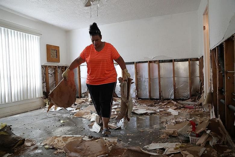 A resident cleaning her home in Houston, Texas, yesterday. Houston Mayor Sylvester Turner said most of the city was "now dry".