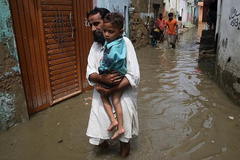 People making their way through a flooded street in Karachi, Pakistan, on Friday. At least 23 people have died in rain-related incidents, mostly due to electrocution, in Karachi in the past two days. India, Nepal and Bangladesh have also endured floo