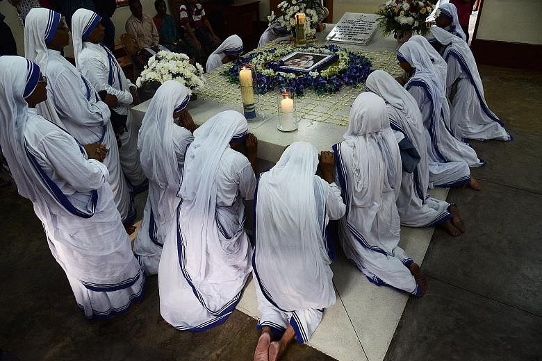 Roman Catholic nuns of the Missionaries of Charity praying at the tomb of Mother Teresa at a service to commemorate the 20th anniversary of her death at the order's house in Kolkata, India, yesterday. Pope Francis on Monday proclaimed Mother Teresa a