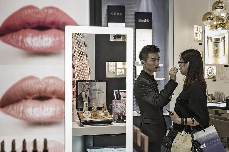 A sales assistant helps a customer try a lip colour in a mall in Shanghai. The Caixin/Markit services purchasing managers' index rose to 52.7 last month - the highest reading in three months - from 51.5 in July.