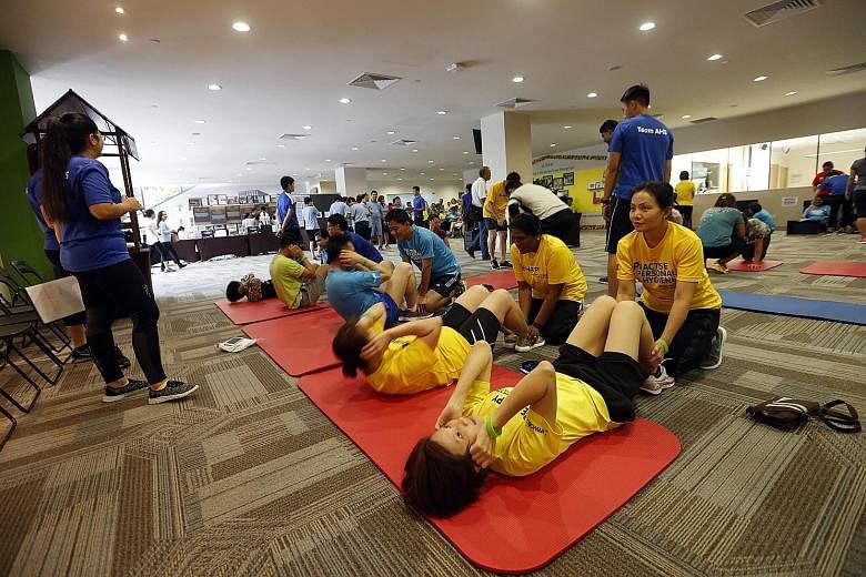 Staff of Khoo Teck Puat Hospital (KTPH) and Yishun Community Hospital doing sit-ups yesterday during an annual fitness challenge, which is held over three weeks. The more than 4,000 staff are encouraged to take part in the challenge, which also inclu
