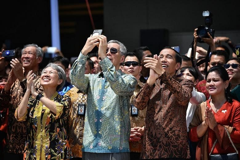 Prime Minister Lee Hsien Loong and President Joko Widodo viewing a joint fly-past by the Singapore and Indonesian air forces yesterday to mark 50 years of diplomatic relations, along with Mrs Lee and First Lady Iriana. Also present was Defence Minist