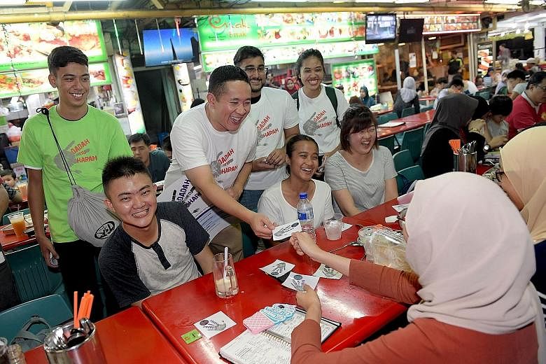 Parliamentary Secretary for Home Affairs Amrin Amin (standing, second from left) and volunteers, including Hairul Marvin (left in green), 17, giving out anti-drug stickers to patrons in Simpang Bedok yesterday.