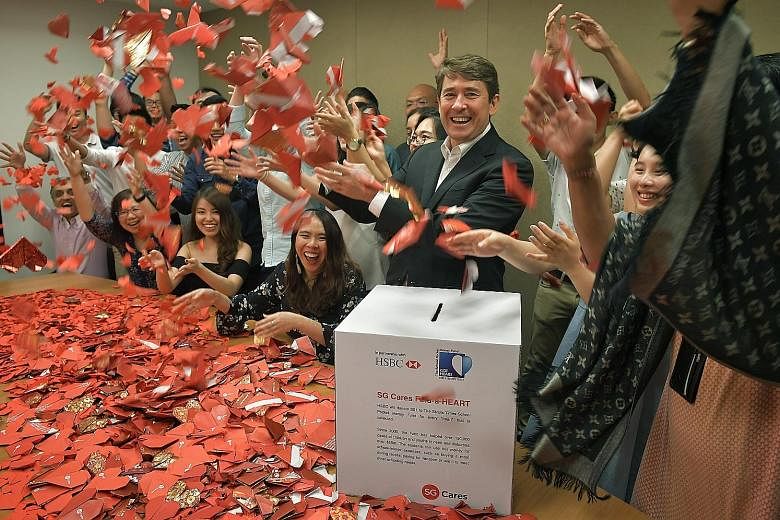 HSBC Singapore's group general manager and chief executive officer, Mr Tony Cripps, and his staff folding the last origami hearts yesterday for the Fold-A-Heart campaign, in which the bank gave $1 to the ST Pocket Money Fund for each folded heart col