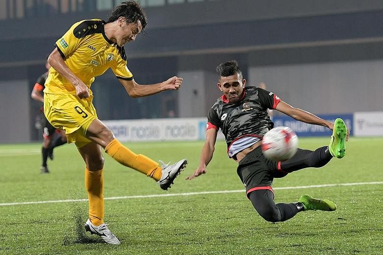 Brunei DPMM's Najib Tarif attempts to block a shot by Tampines' Ryutaro Megumi during their S-League match in July. Uncertainty surrounds the competition as a funding cut may force the league to shut down.