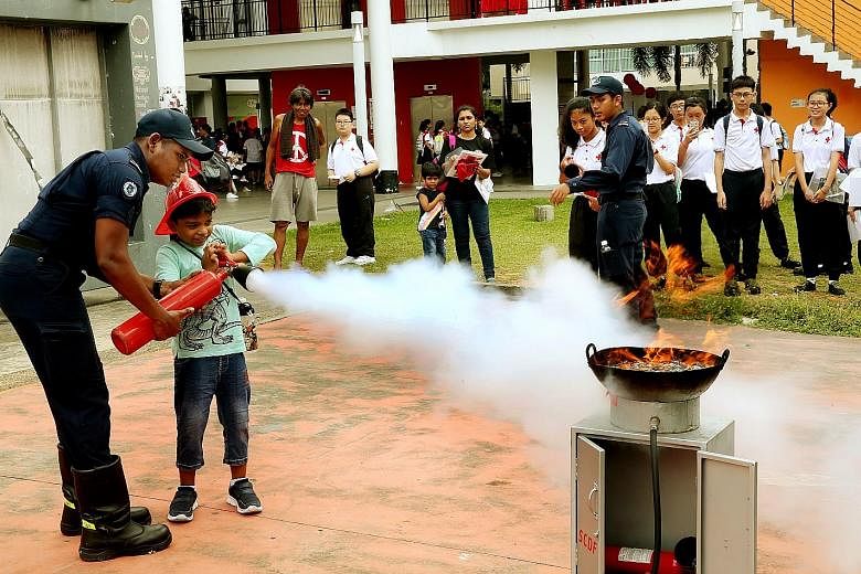 Dinesh Durai Kannan, nine, learning how to use a fire extinguisher at yesterday's event at Taman Jurong Community Club where the Singapore Red Cross was marking World First Aid Day with a carnival.