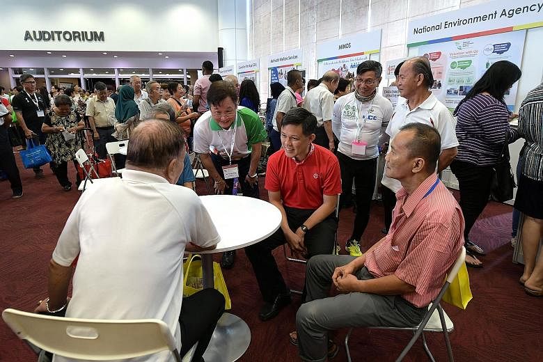 Minister in the Prime Minister's Office Chan Chun Sing and senior volunteer group RSVP Singapore's president Koh Juay Meng (in white and green shirt) chatting with participants at the launch of a scheme yesterday to encourage older workers to become 