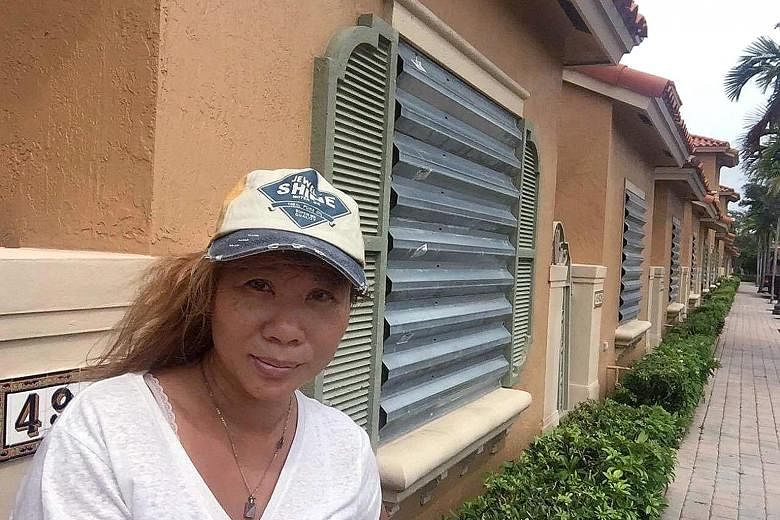 Ms Selina Seet outside her home in Florida. She has gone into lockdown mode, with her windows and patio doors boarded up by hurricane shutters.