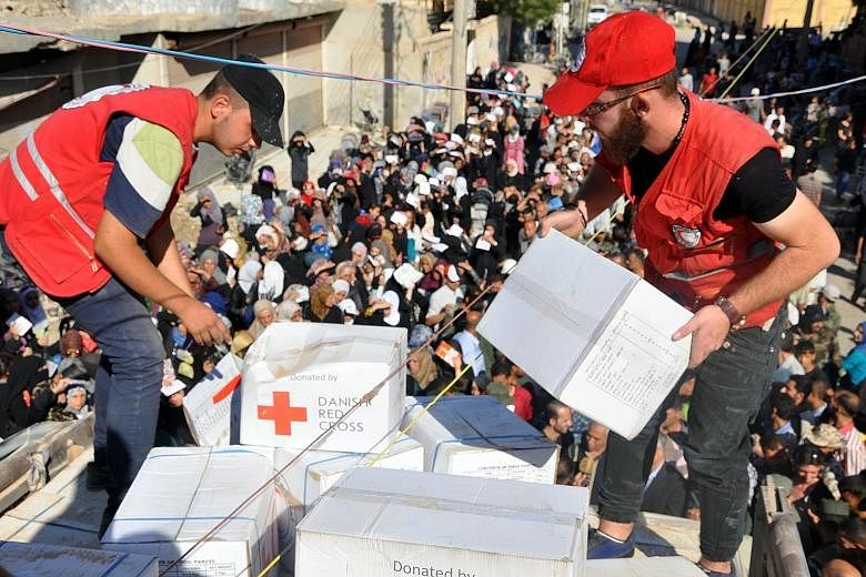 Members of the Syrian Red Crescent distributing aid parcels to Deir Ezzor residents on Saturday. Large crowds gathered to receive bags of rice, bulgur wheat, olive oil and preserves, as well as hygiene products.