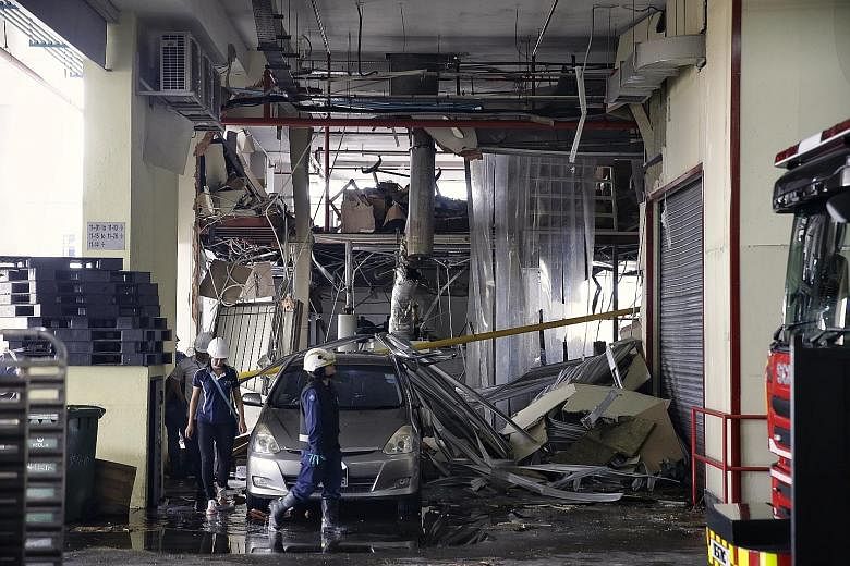 A Singapore Civil Defence Force officer and Manpower Ministry staff surveying the damage caused by an explosion at an 11th-floor unit at Enterprise Centre in Bukit Batok Crescent. Windows were shattered and frames left dangling after the blast, but t