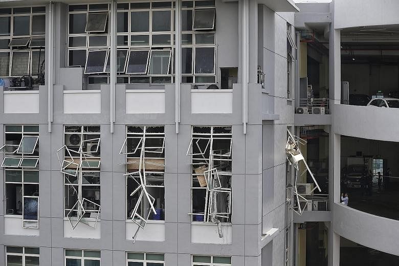 A Singapore Civil Defence Force officer and Manpower Ministry staff surveying the damage caused by an explosion at an 11th-floor unit at Enterprise Centre in Bukit Batok Crescent. Windows were shattered and frames left dangling after the blast, but t