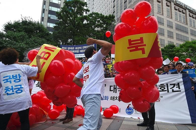 South Korean activists bursting balloons with yellow banners reading "ICBM" and "SLBM" - the acronyms for intercontinental ballistic missile and submarine- launched ballistic missile - during a rally in Seoul yesterday to denounce North Korea's sixth