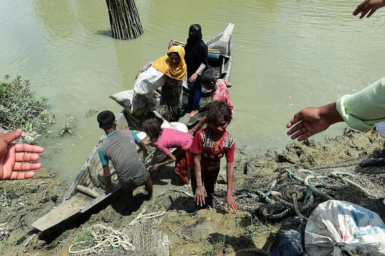Bangladeshis helping Rohingya Muslim refugees to disembark from a boat on the Bangladeshi side of Naf River yesterday.