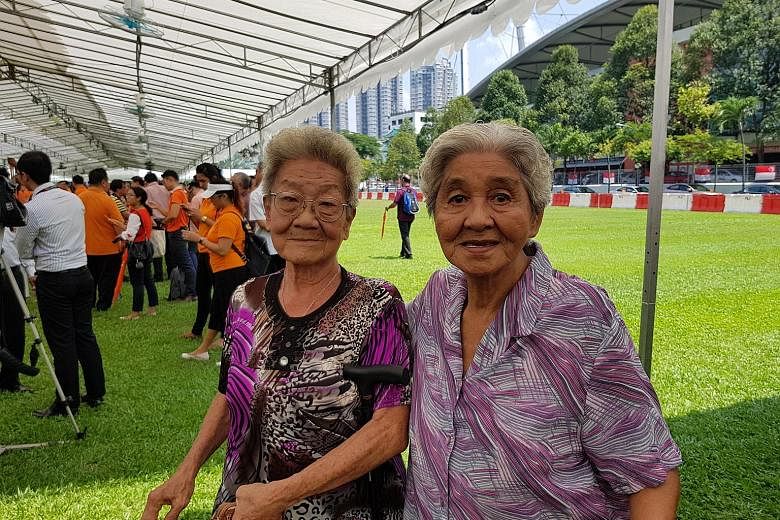 Residents Lim Ah Kheoh (far left) and Sim Goon Hua walked to the nomination centre to try and catch a glimpse of Madam Halimah yesterday.