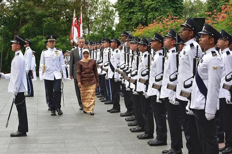 President Halimah Yacob, accompanied by Prime Minister Lee Hsien Loong, inspecting the guard of honour during the welcome ceremony for the new President at the Istana yesterday.
