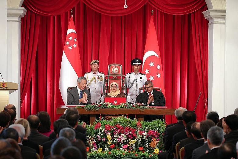 President Halimah Yacob, flanked by Prime Minister Lee Hsien Loong and Chief Justice Sundaresh Menon, getting a round of applause at the end of her speech at the Istana yesterday. Madam Halimah said her duty as President is to "unite the people, to o