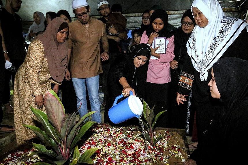 Ms Norazlin Abd Aziz watering the grave of her son Muhammad Afiq Haqiemie Hairulizwan, 11, one of the victims of the fire at Darul Quran Ittifaqiyah tahfiz school, after he was buried at the Jalan Ampang Muslim cemetery yesterday. Ms Siti Halijah, an