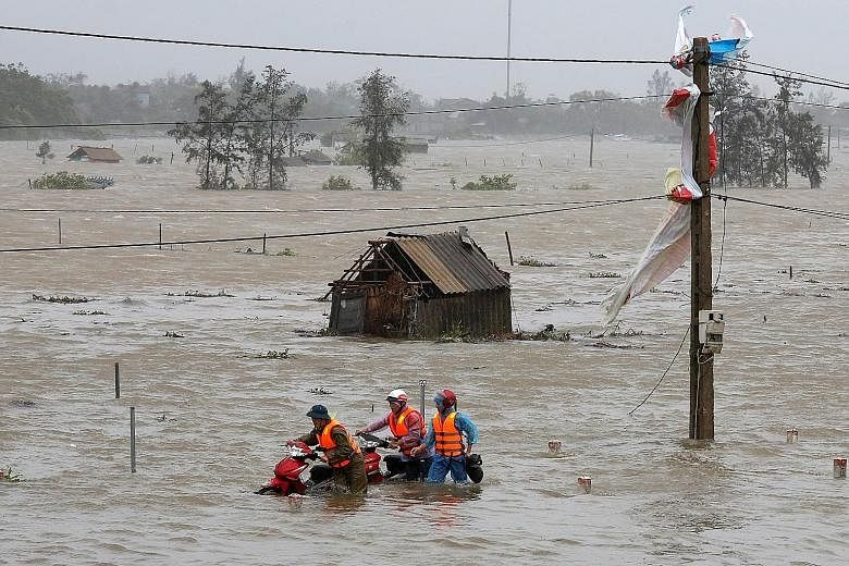 People in Ha Tinh province wading through flood waters yesterday. Vietnam has been hit by severe weather several times this year, with about 140 people dead or missing in natural disasters since January.