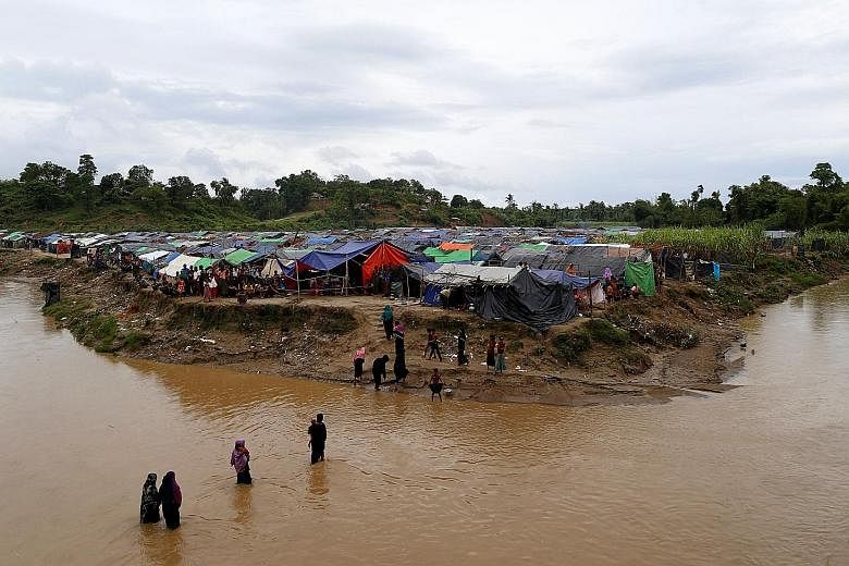 Rohingya refugees crossing a stream to reach their temporary shelters in the no-man's-land between Bangladesh and Myanmar on Sept 9. For now, they have regular food deliveries and access to clean water and medicines, thanks to the local commander of 