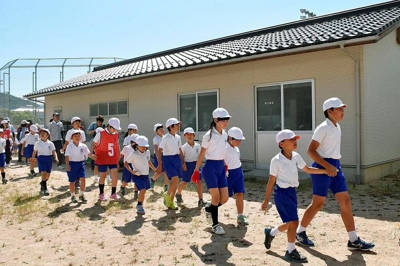 Elementary school pupils taking part in an evacuation drill for a simulated North Korean missile attack in Japan's Yamaguchi prefecture in June.