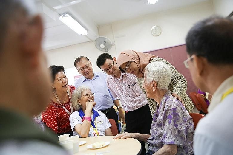 President Halimah Yacob, with THK Moral Charities chairman Lee Kim Siang (in light blue shirt), on a visit to the THK Indus Moral Care seniors activity centre in Tiong Bahru yesterday. The charity offers a drop-in disability programme at four of its 