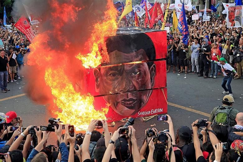 Protesters burning a cube effigy displaying the face of Philippine President Rodrigo Duterte during a "National Day of Protest" outside the presidential palace in Metro Manila yesterday.