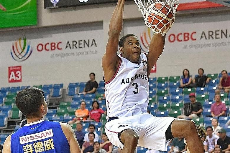Adelaide 36ers forward Ronald Roberts executing a two-handed slam dunk at the Merlion Cup basketball tournament at the OCBC Arena yesterday, as Yulon Luxgen Dinos' captain Lee Te-wei watches on. The American import scored 19 points as the Sixers thra
