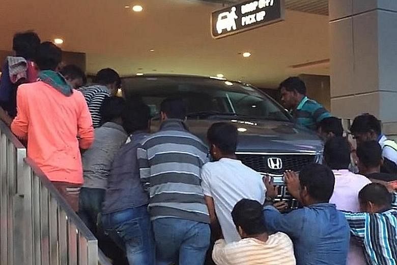 A group of foreign workers pushing a car back to level ground after it ended on a flight of stairs at the Waterway Point mall in Punggol yesterday. Facebook user Garett Lim, 38, who posted a video of the incident, told The Straits Times that the car 