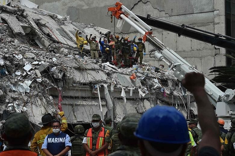 Rescuers and firefighters raising their fists to pay their respects to a man who survived the quake but died before they could reach him during their search for survivors at a flattened building in Mexico City on Thursday.